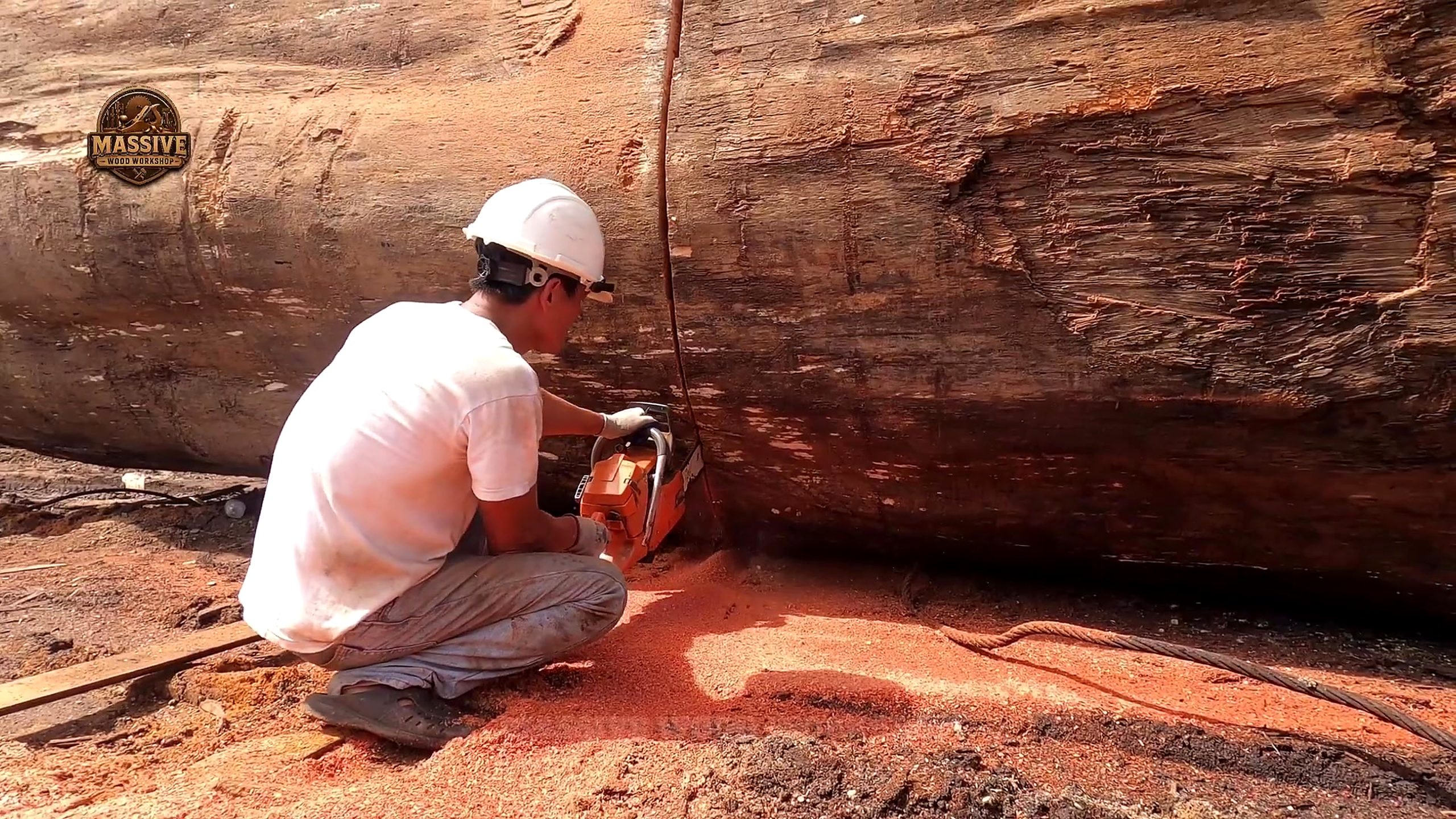 giant log round tabletop cutting process with a worker using a chainsaw beside the bark