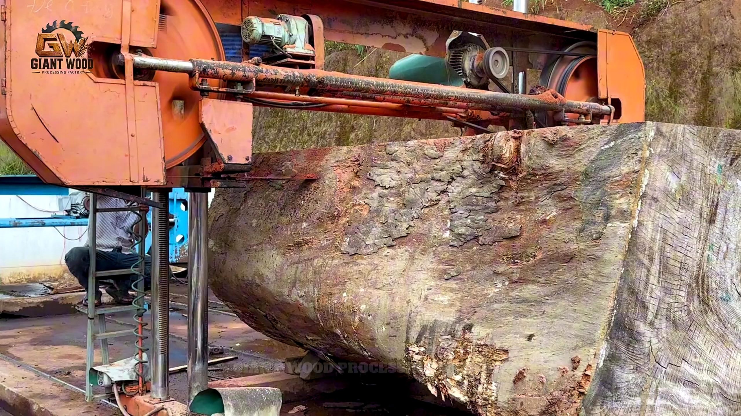 3000 year old timber sawmill slab process - the orange frame saw positioned against a large squared timber section