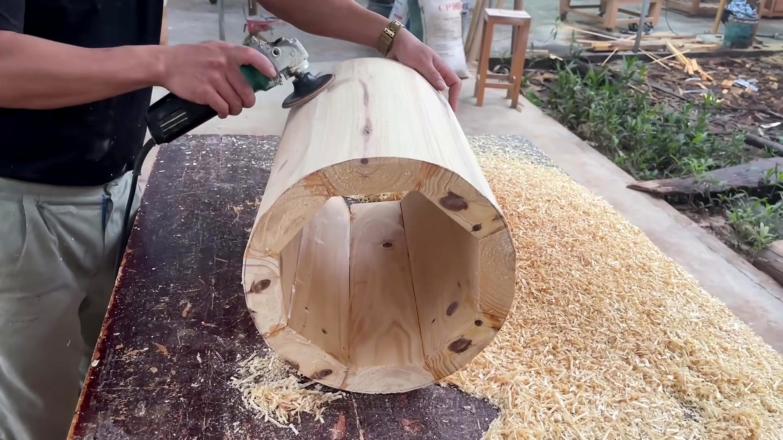 circular wood pedestal lattice furniture workflow - a hollow cylindrical wood form being cut and cleared while chips collect around the work