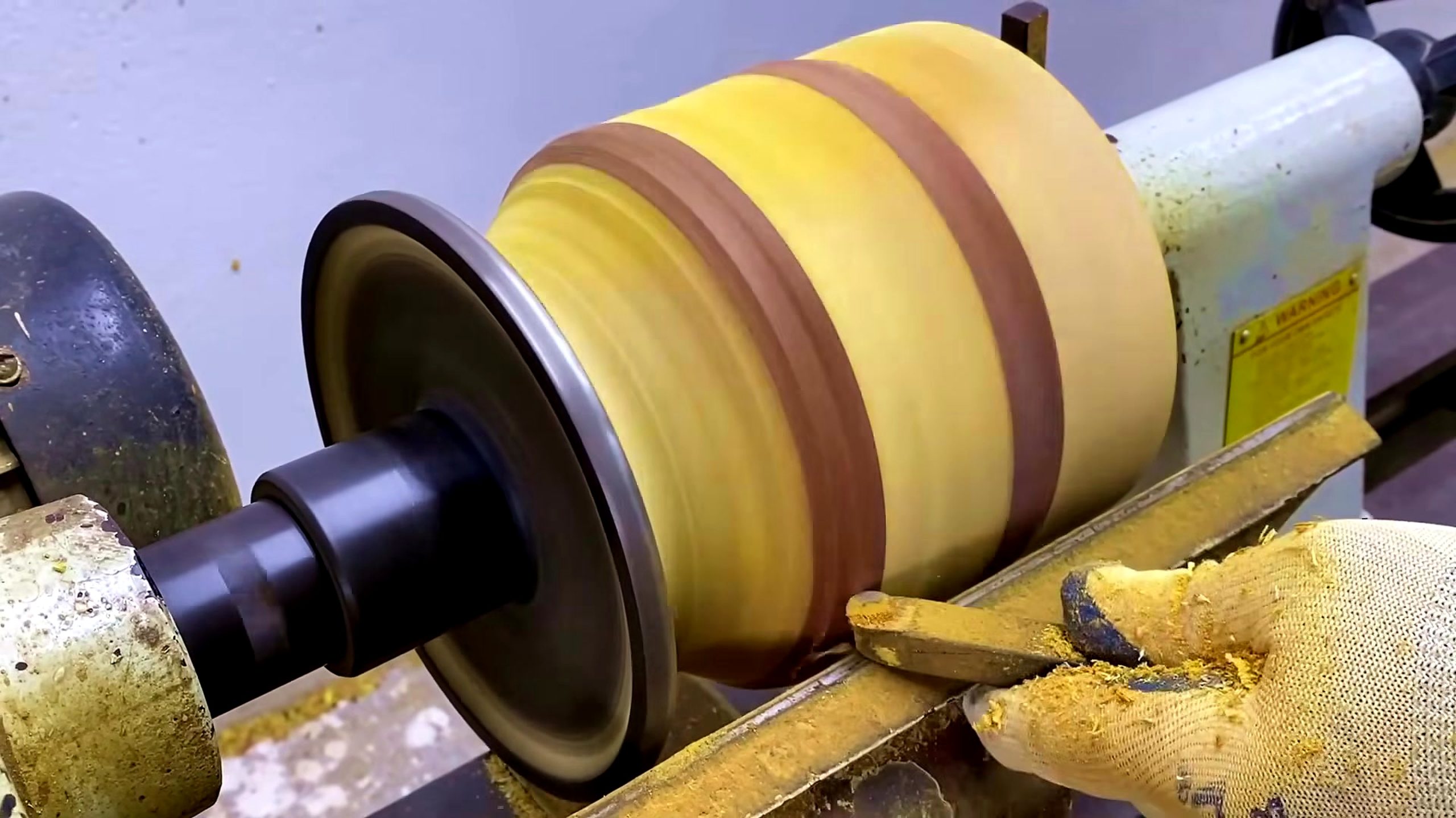 laminated wood bowl turning process - the striped laminated blank spinning on a wood lathe during outside shaping