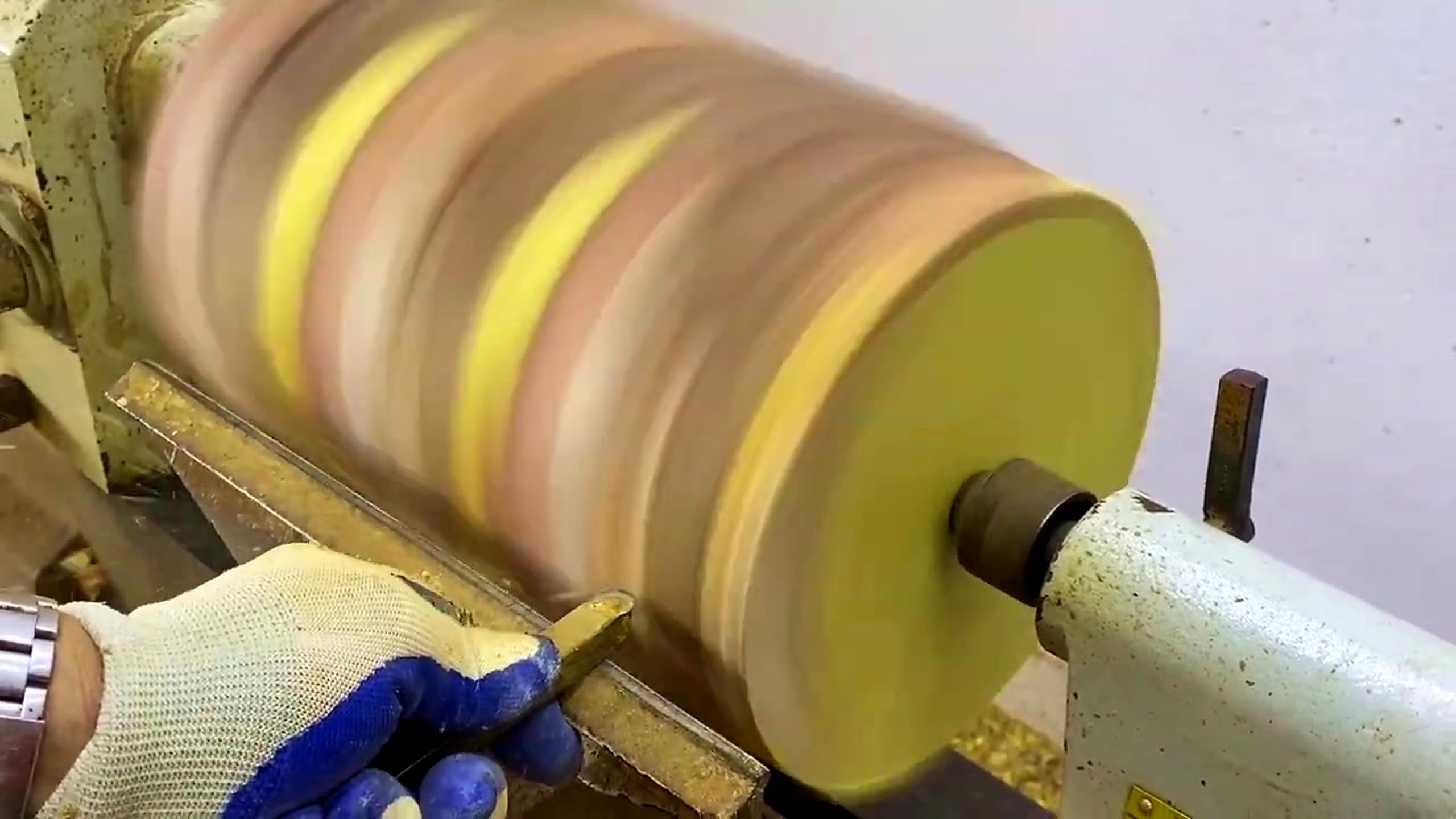 striped laminated wood lathe form process - the striped blank rotating between centers while the outside form begins to round