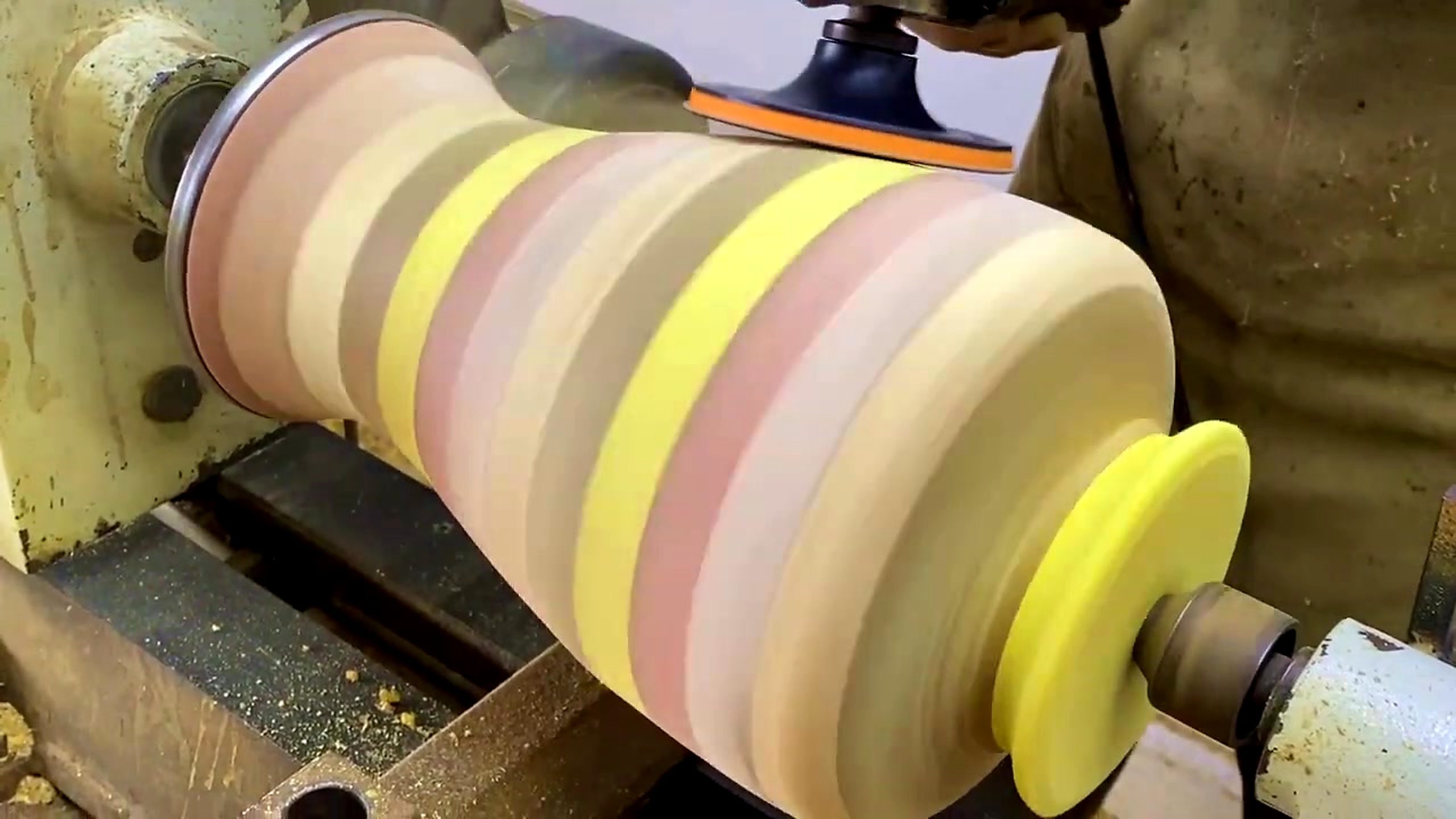 striped laminated wood lathe form process - the rotating striped form being sanded and reviewed near the final profile stage