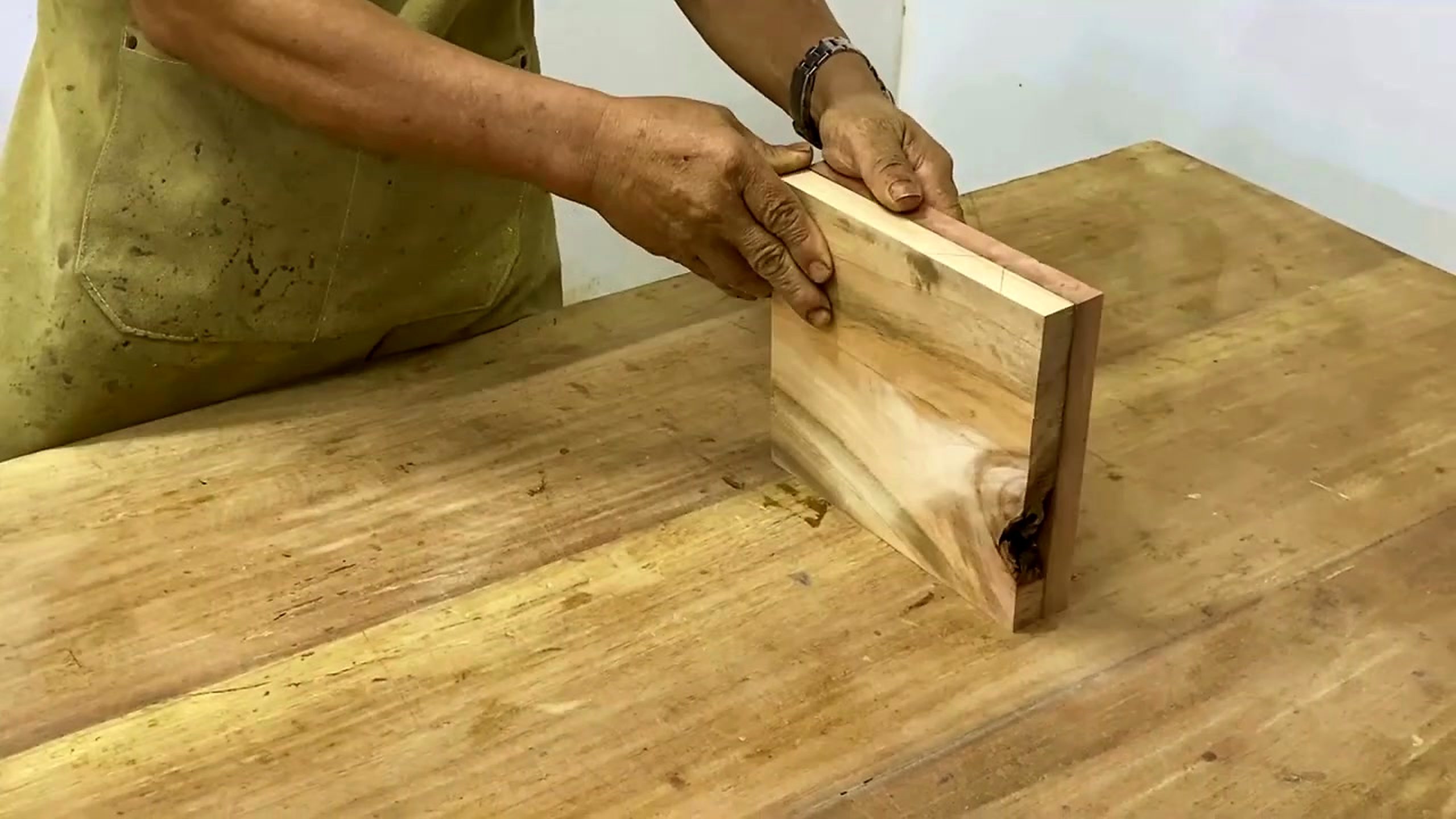 striped laminated wood lathe form process - a rectangular wood block being handled on the bench before the laminated layout is judged