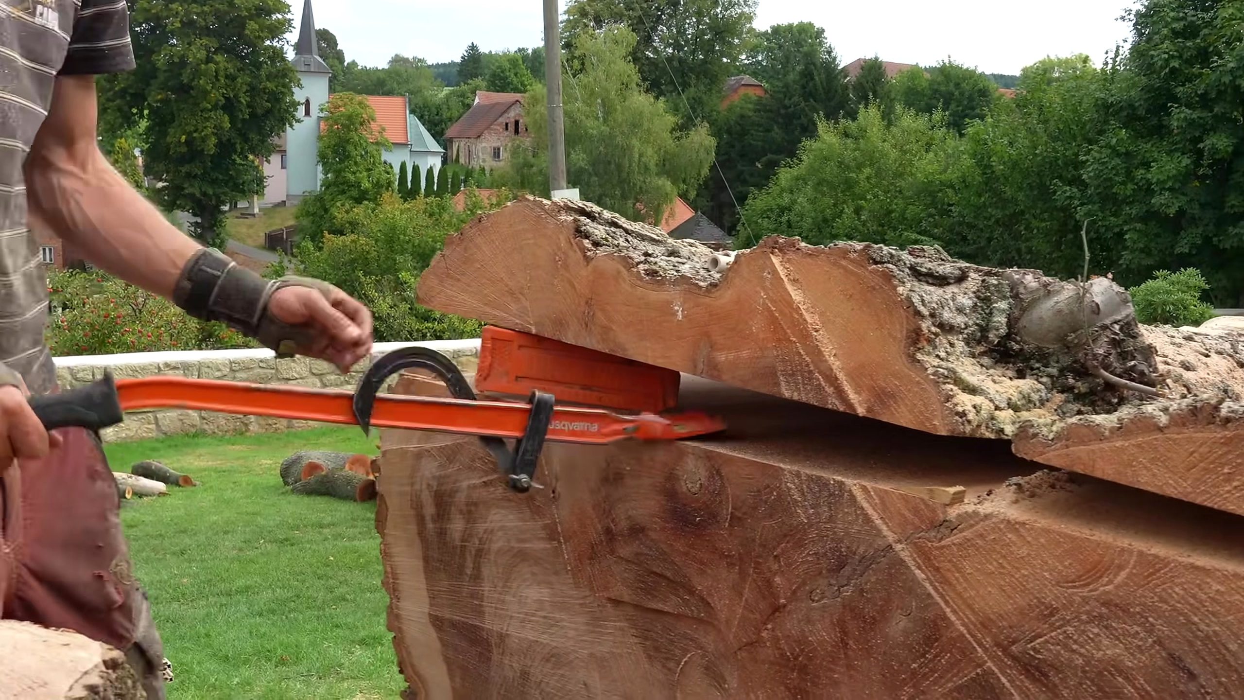 chainsaw milling giant log into solid boards - the long chainsaw bar and portable guide controlling a longitudinal milling pass