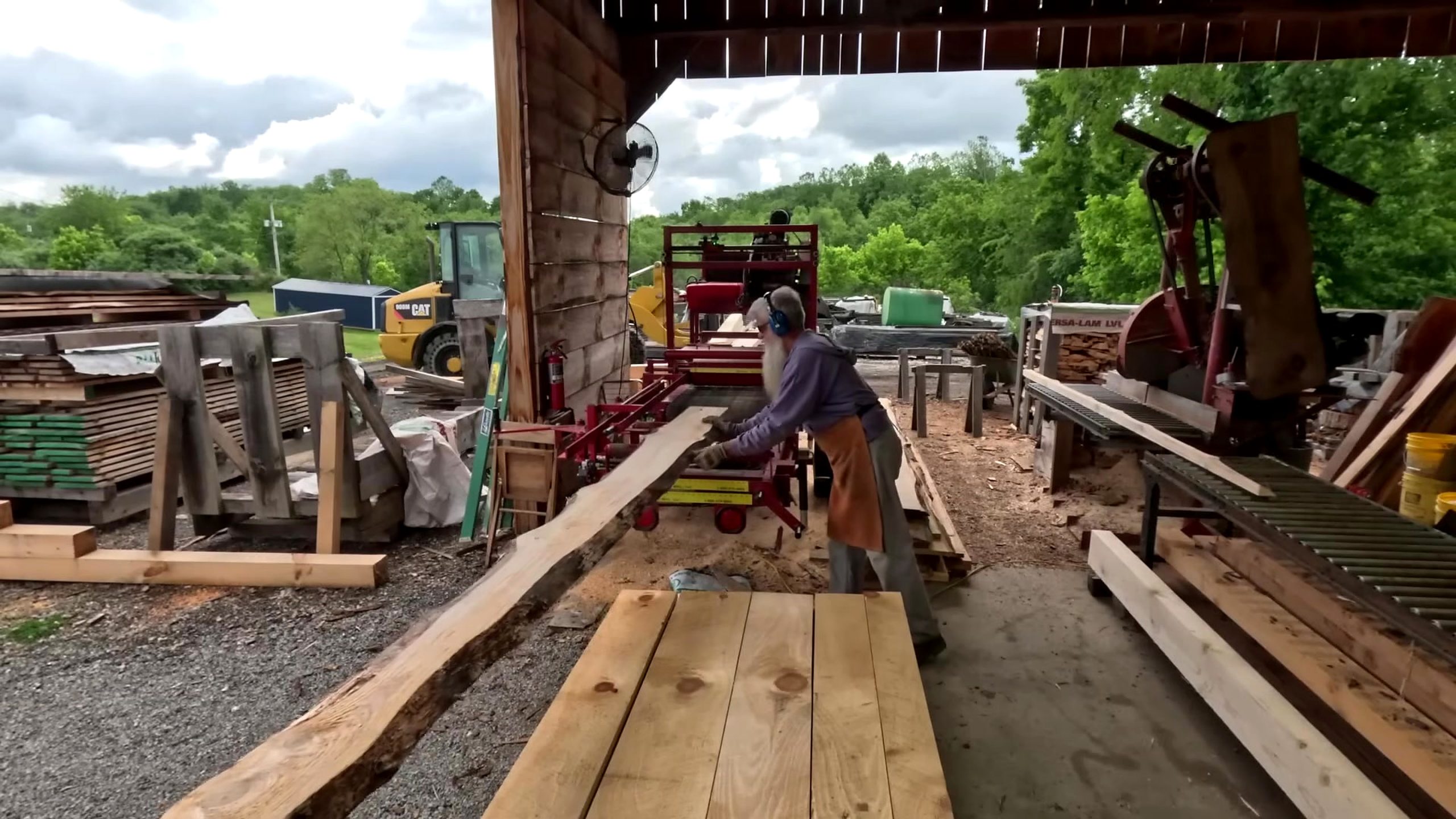 operator handling long fresh-sawn stock after sawing 2x8 boards for a shed floor