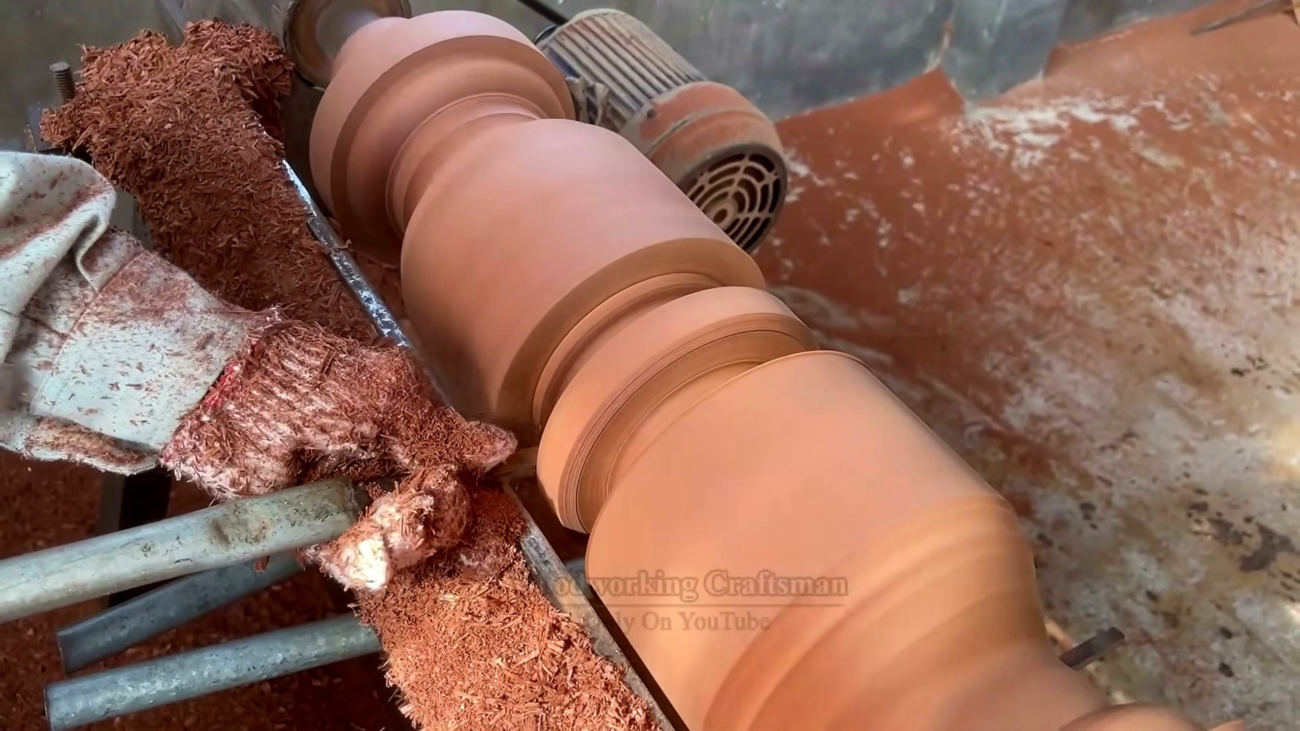 giant twisted burl lychee wood root - long profiled spindle rotating on a lathe during staged turning