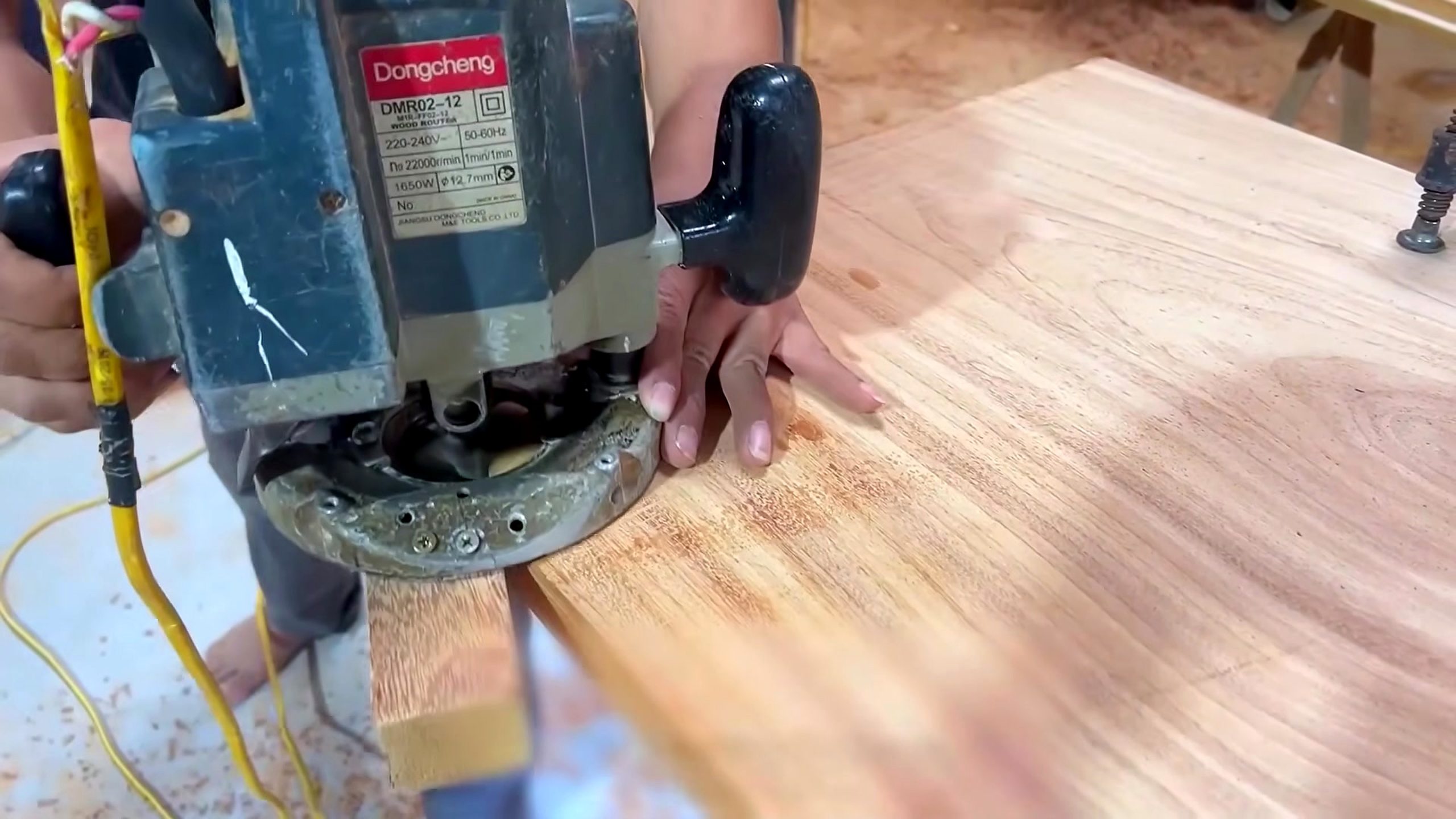hardwood cabinet frame and panel process - a handheld router cutting a controlled recess near a broad panel edge