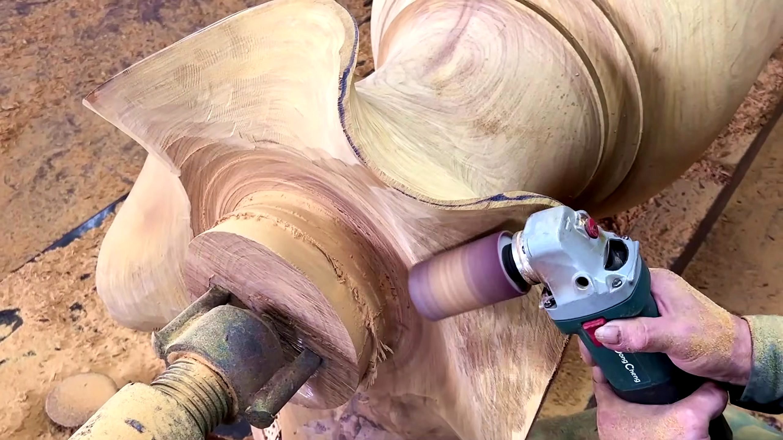 large wood log lathe turning process - an abrasive carving tool refining the lobed foot after rotational shaping