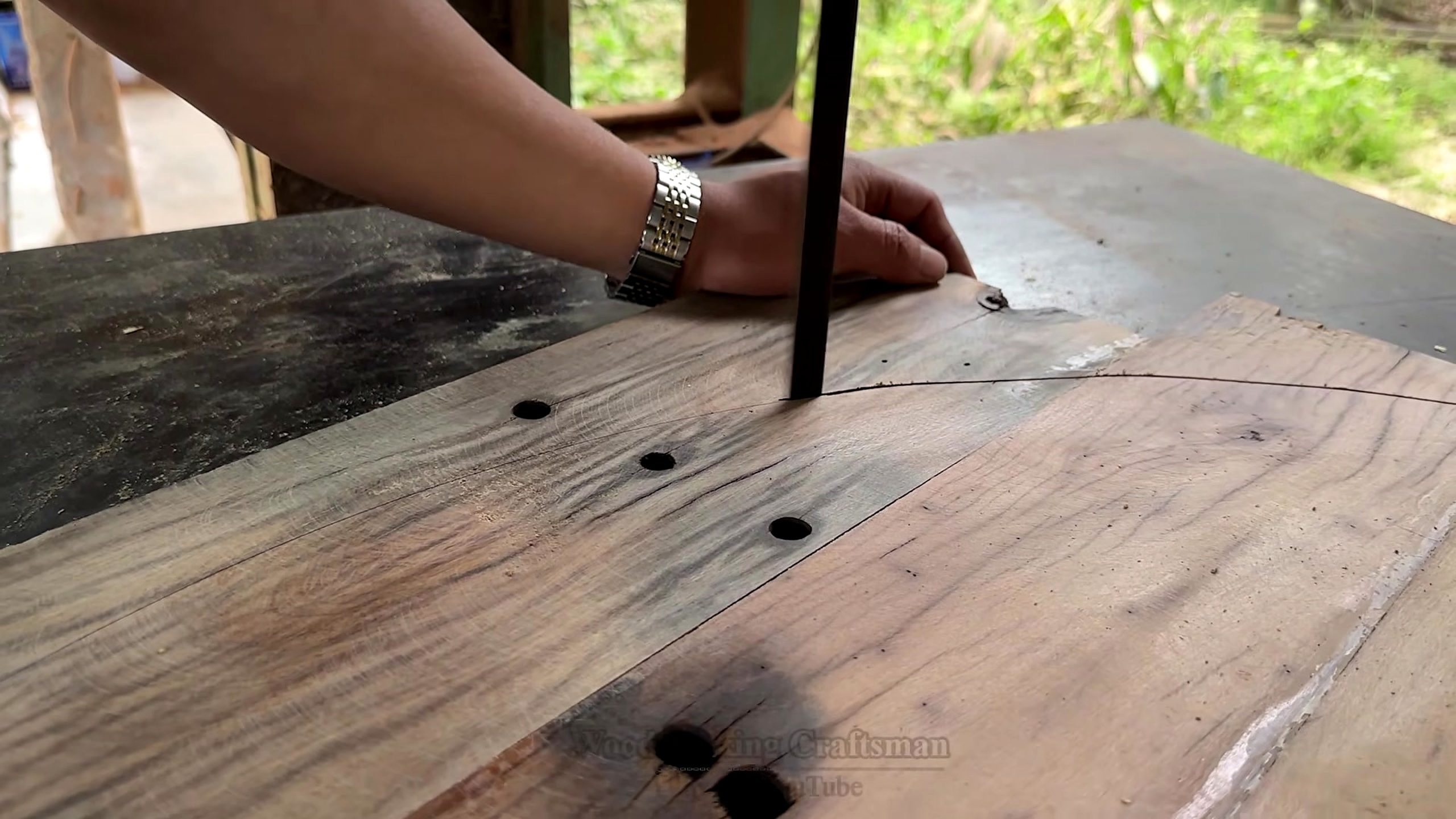 old wood furniture carpentry project - a wide board being cut along a marked curve on a vertical blade setup