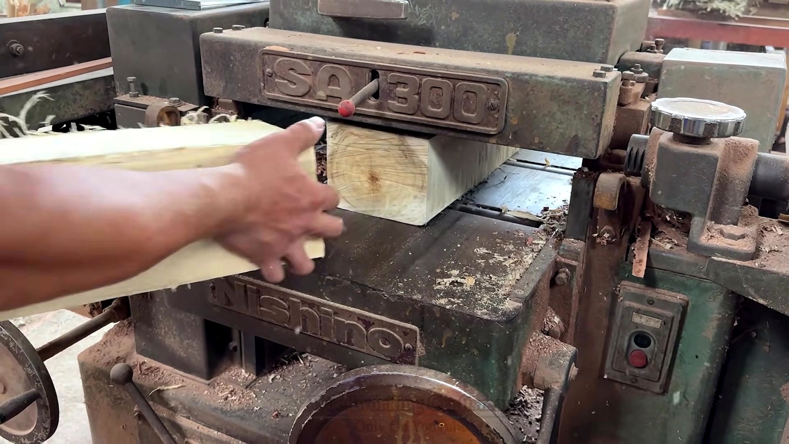 old wood furniture carpentry project - a small block being pushed through a heavy shop machine for sizing or squaring