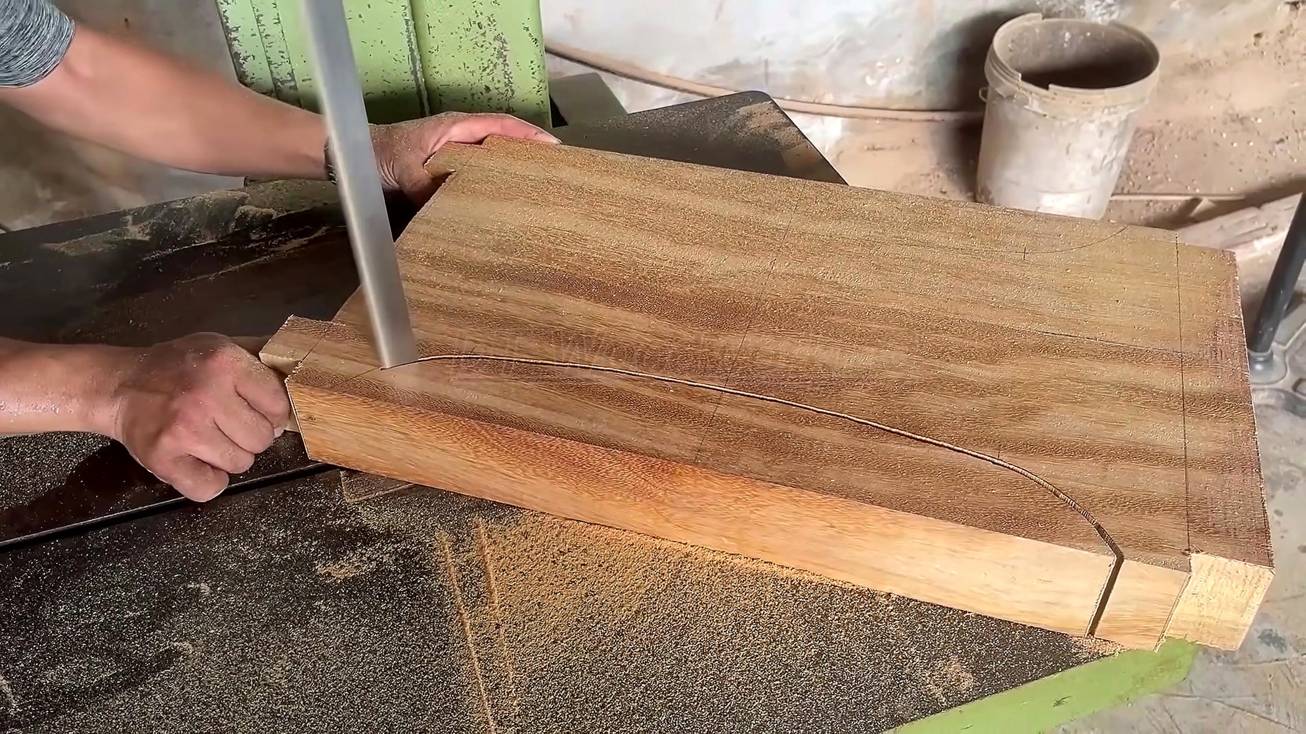 solid wood furniture frame joinery process - a thick support component being bandsawn to a curved furniture profile