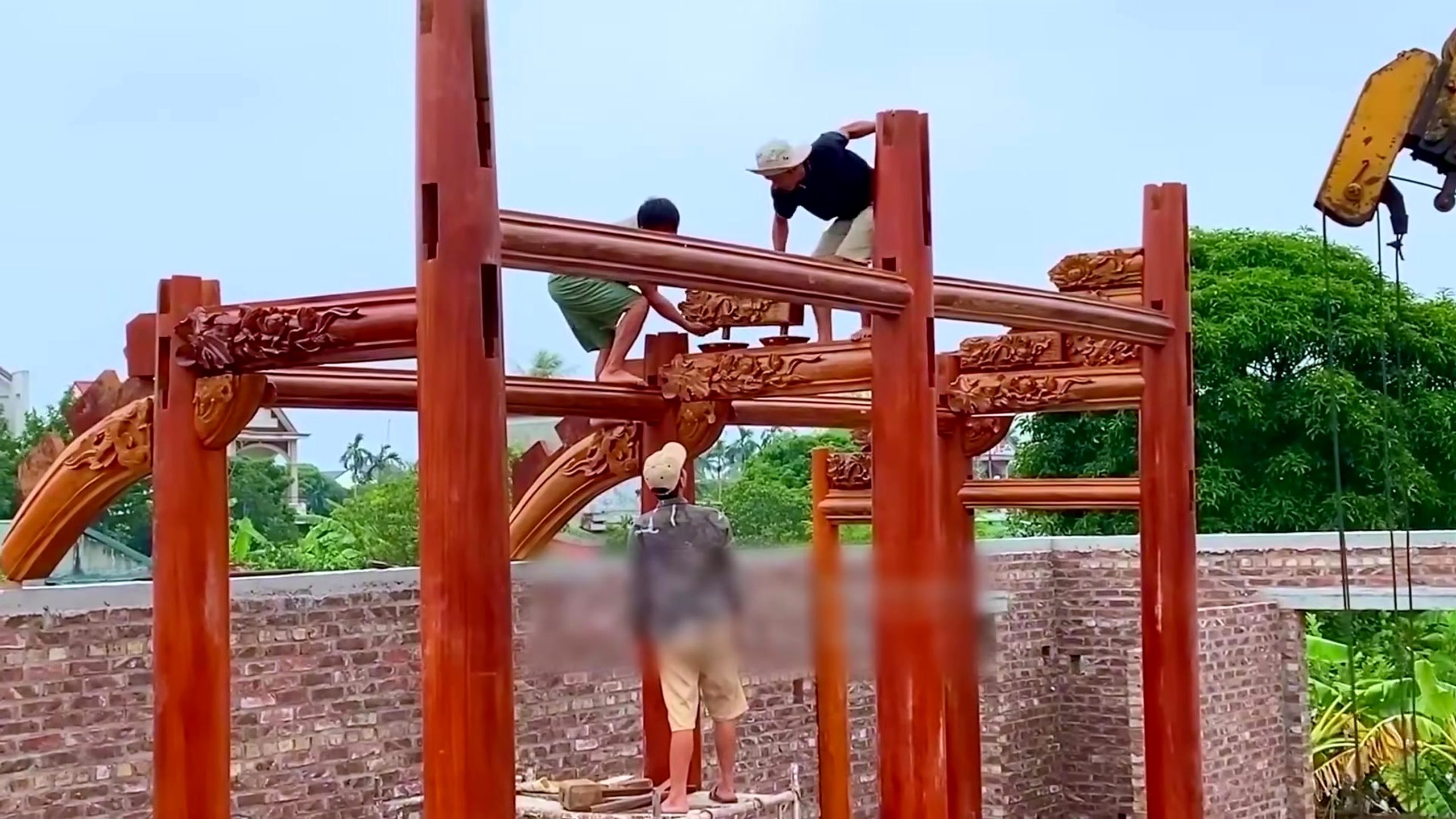 traditional timber frame mortise and tenon assembly - workers guiding a decorated horizontal timber between two upright posts