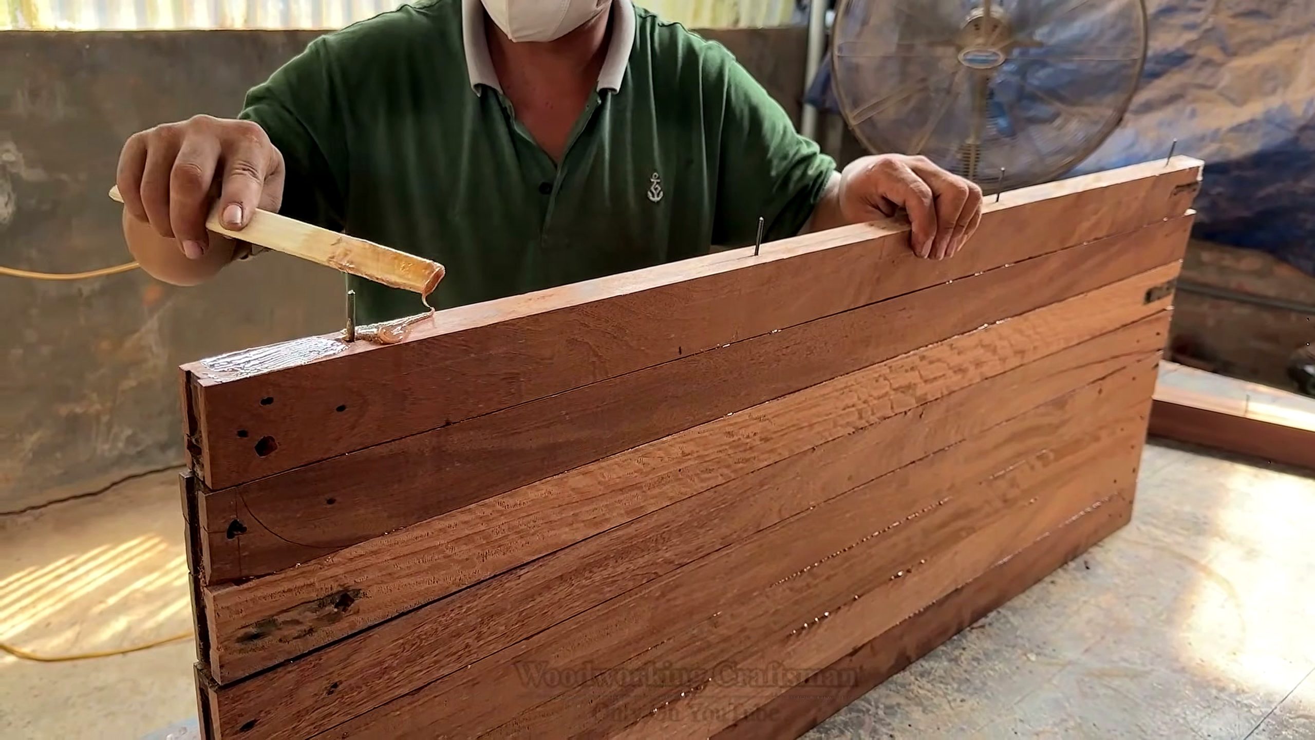 using centuries old decayed warped wood - glue being spread across a long reclaimed slat assembly before the rounded shell is formed