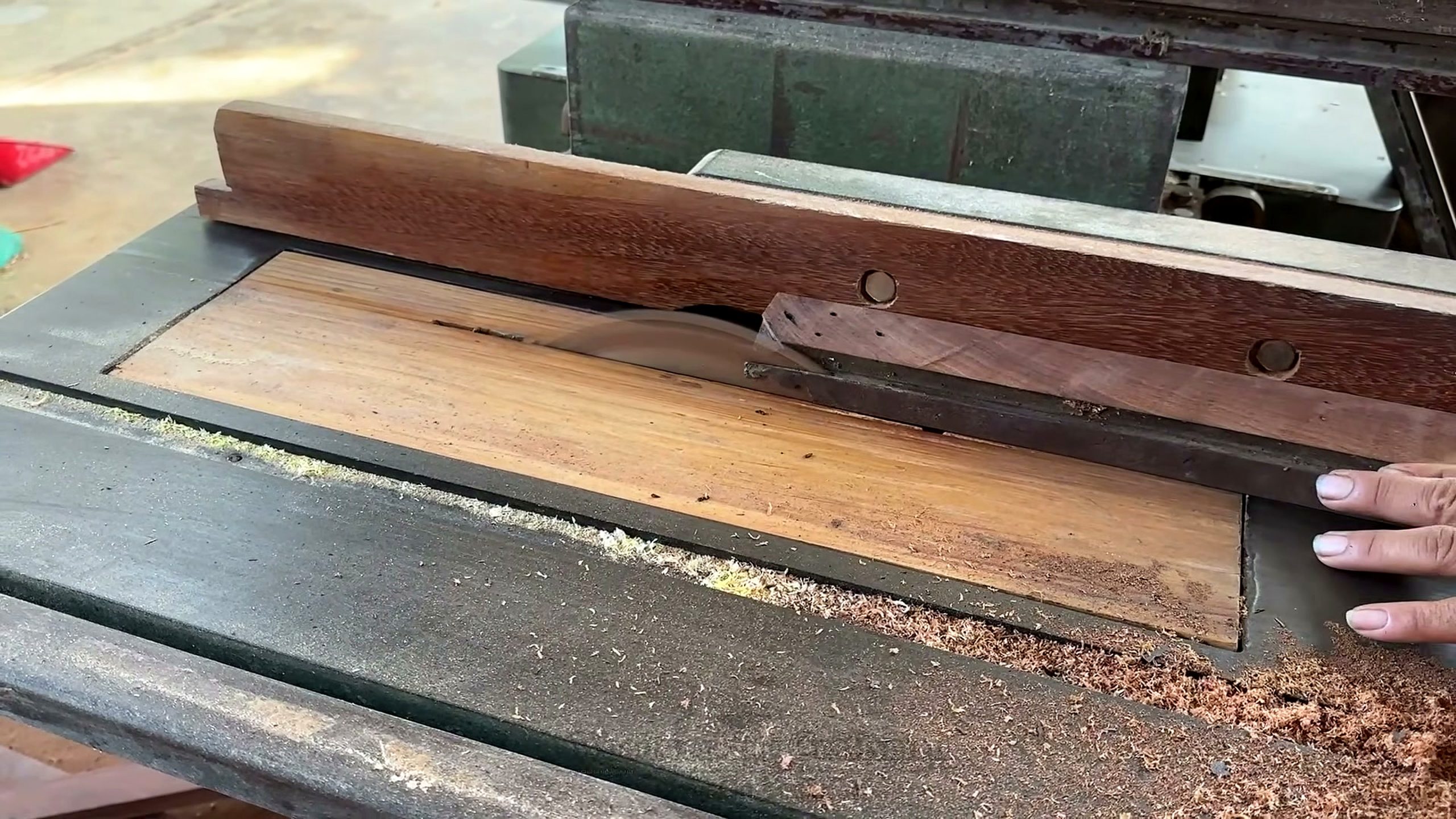 using centuries old decayed warped wood - a reclaimed dark board being ripped on a table saw to create a straight reference edge