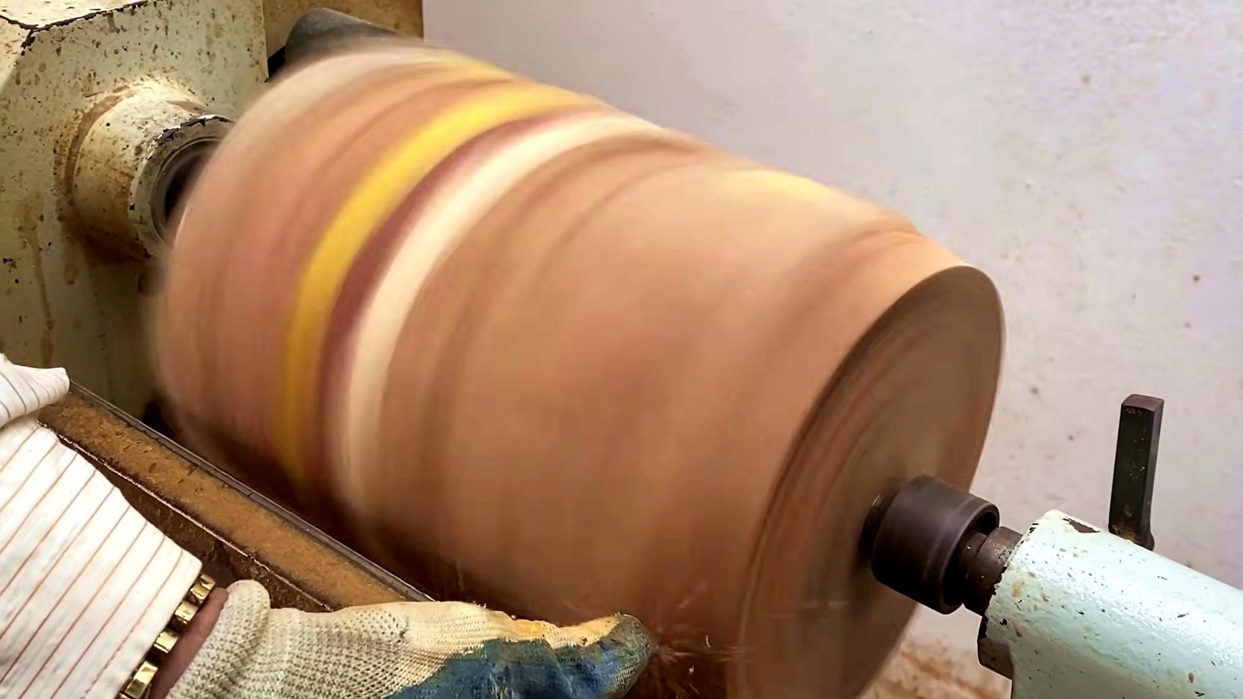 wooden tool lathe turning process - a striped wooden blank spinning on a lathe during early roughing