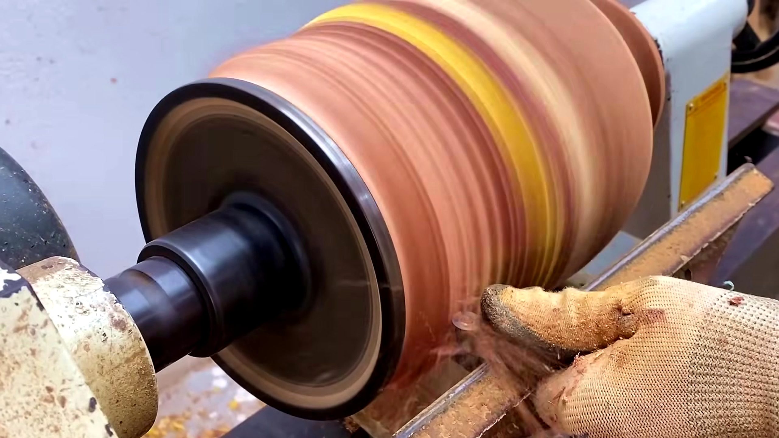 wooden tool lathe turning process - a gloved hand and turning tool controlling the cut from the tool rest