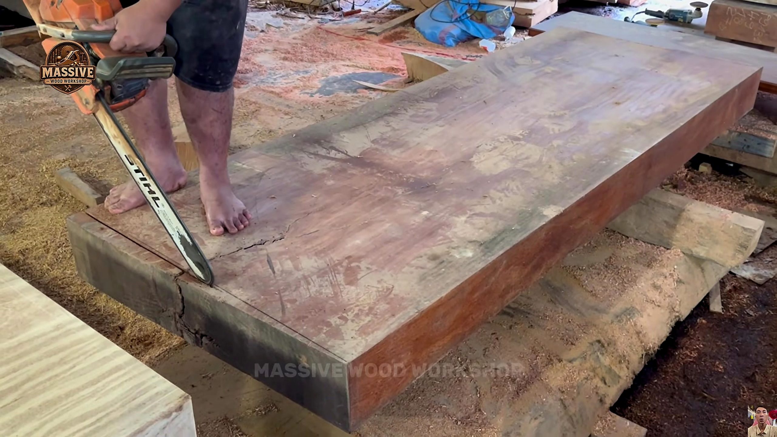 giant log bandsaw slab table process - a chainsaw following a marked cut near the end of the thick slab