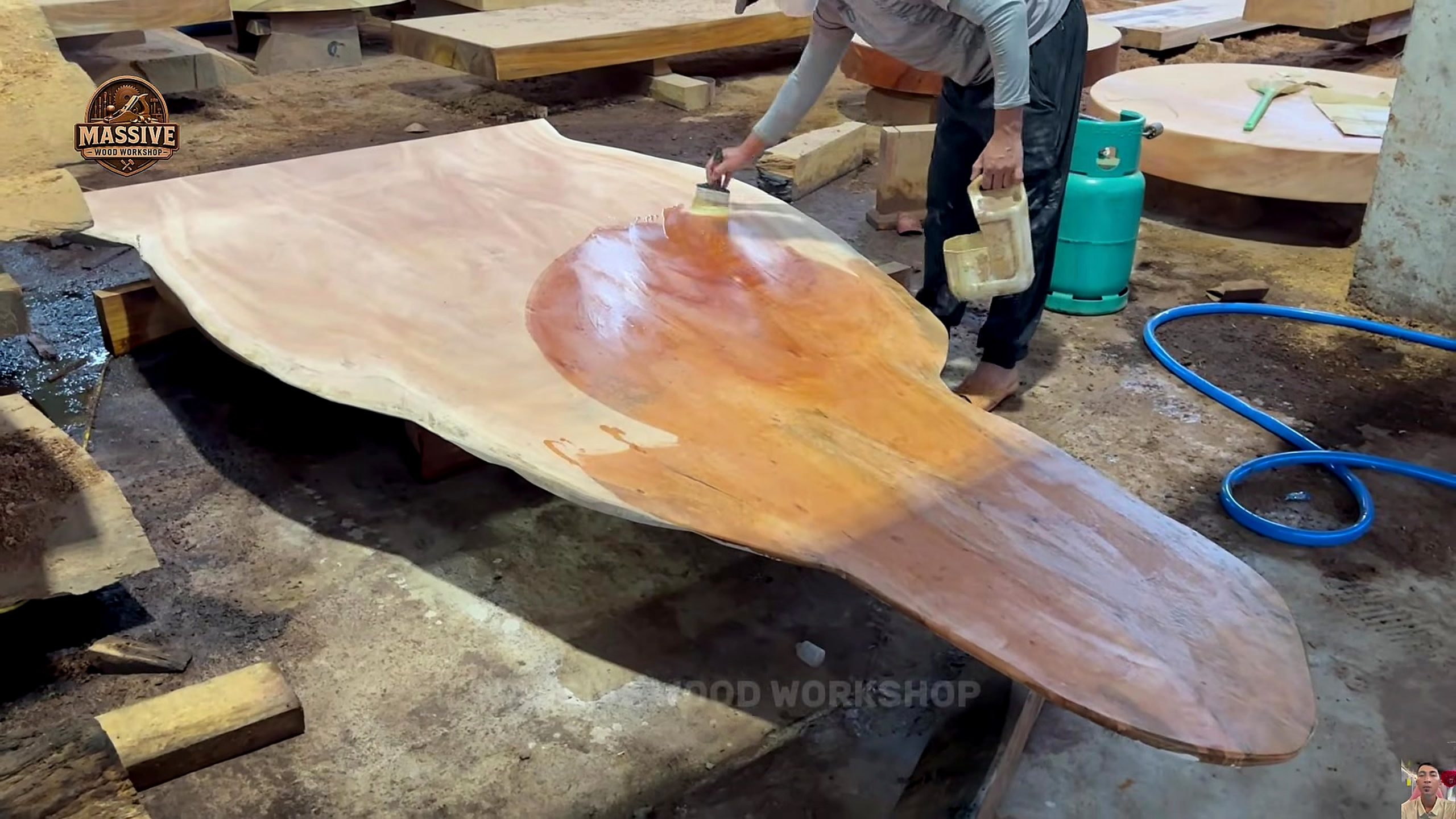 giant log bandsaw slab table process - liquid finish being brushed across the organic live-edge tabletop