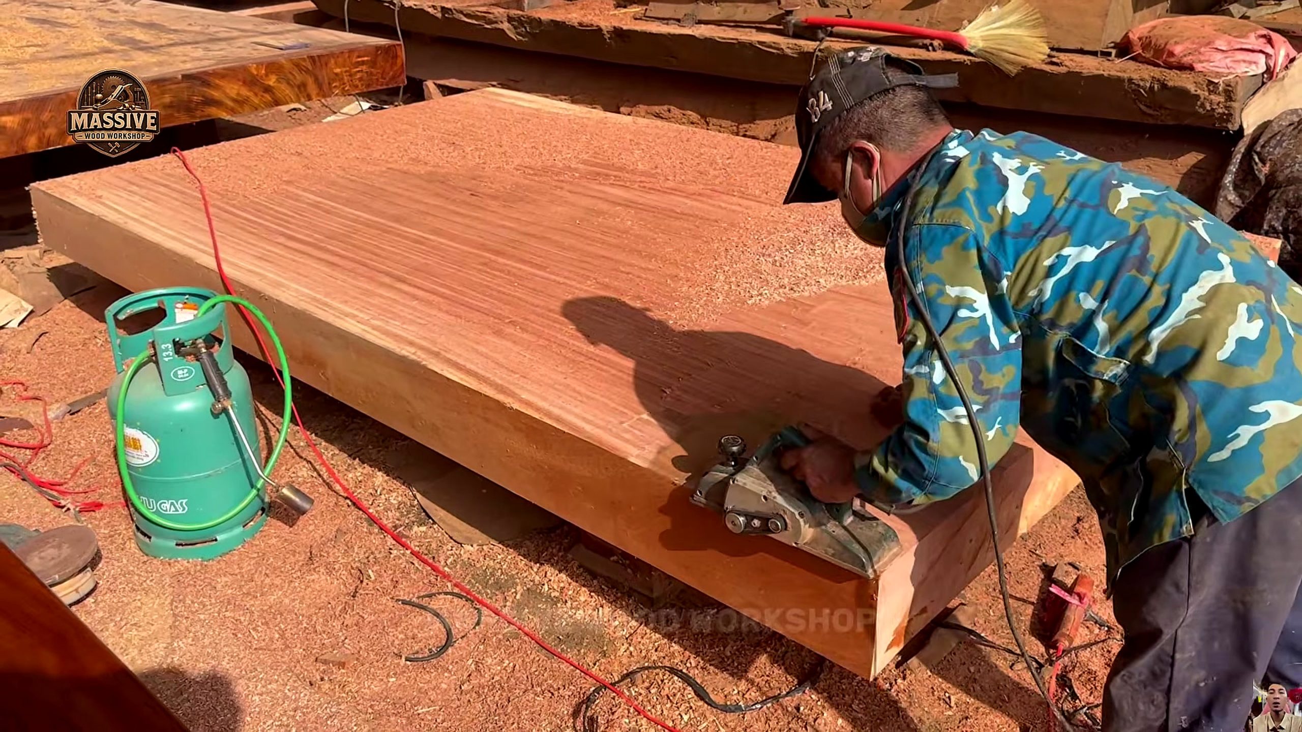 giant log bandsaw slab table process - a powered hand planer making parallel passes across the slab face