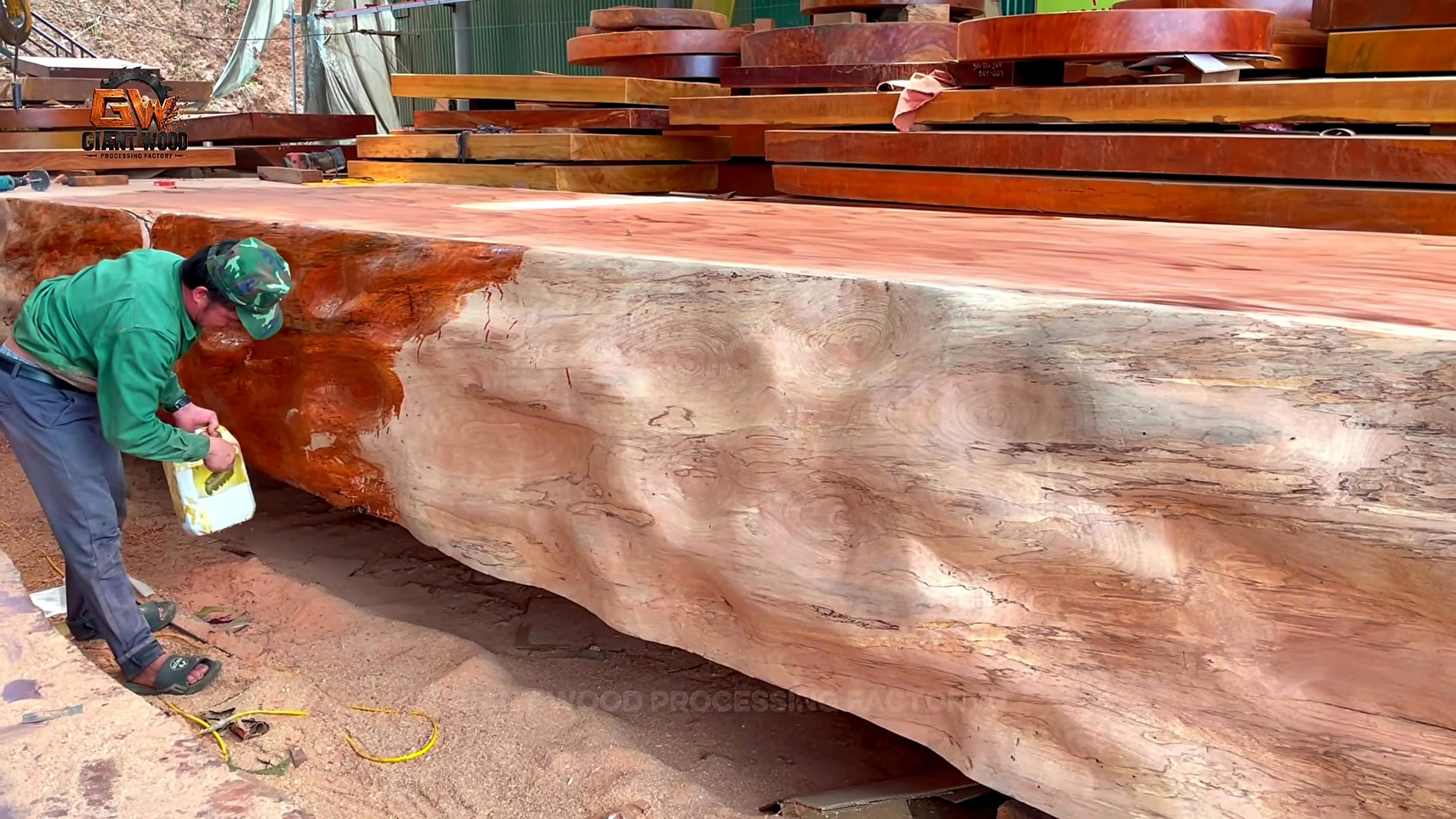 giant log vertical bandsaw sculptural table process - liquid being applied to the irregular outer face of the massive supporting timber