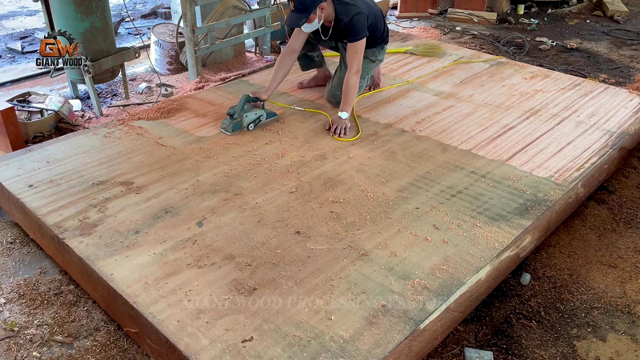 inside million wood factory giant log - worker making powered overlapping passes across a wide slab