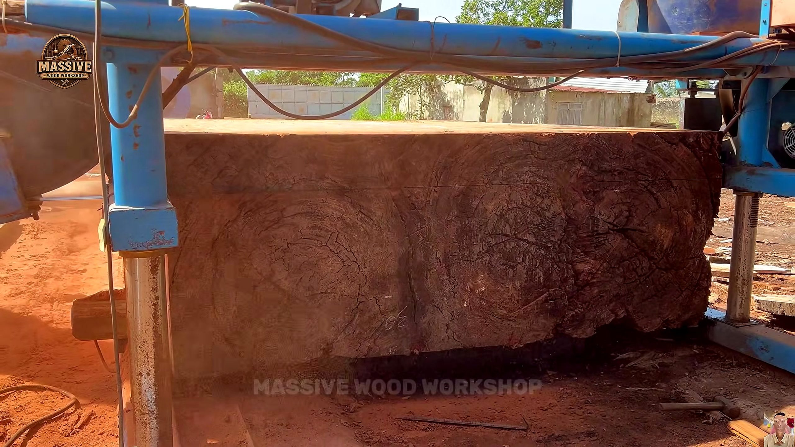 weathered giant timber round table process - the supported timber moving through the blue vertical bandsaw