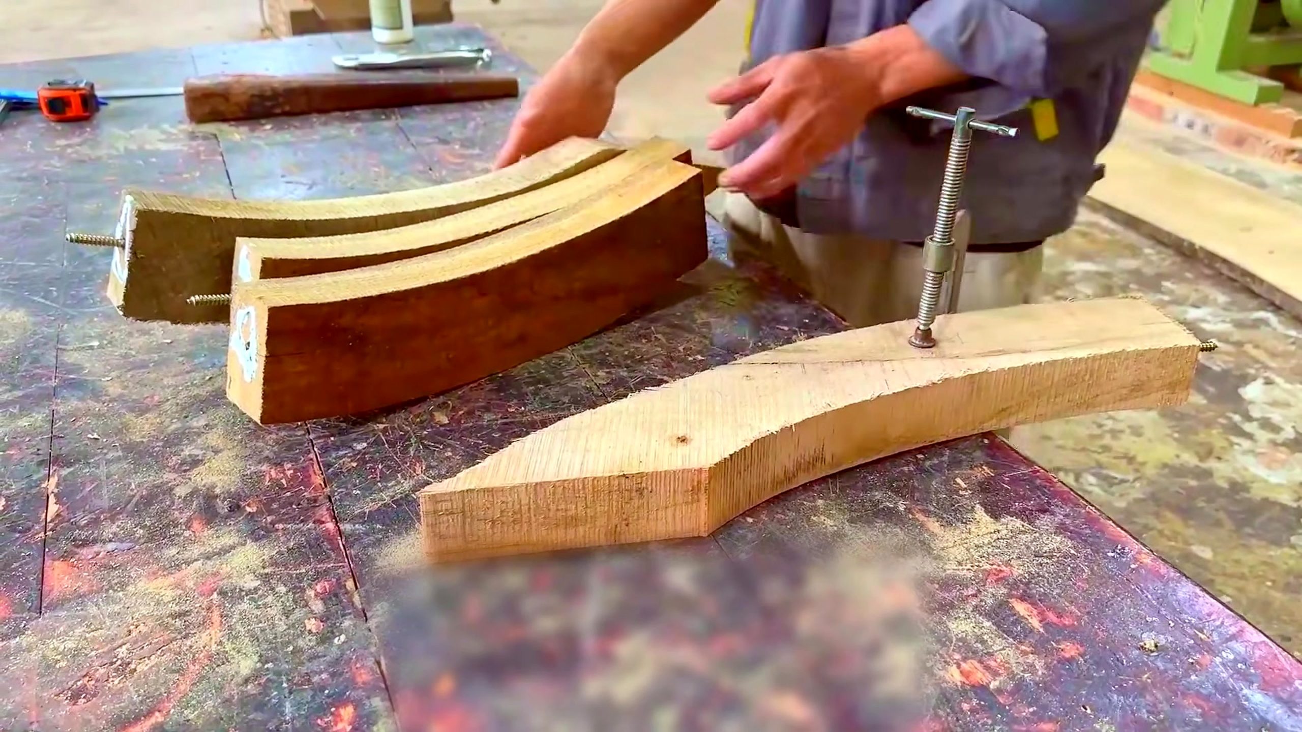 wood and bamboo pavilion build with miter saw - repeated curved wooden roof members being compared and fastened on the workbench