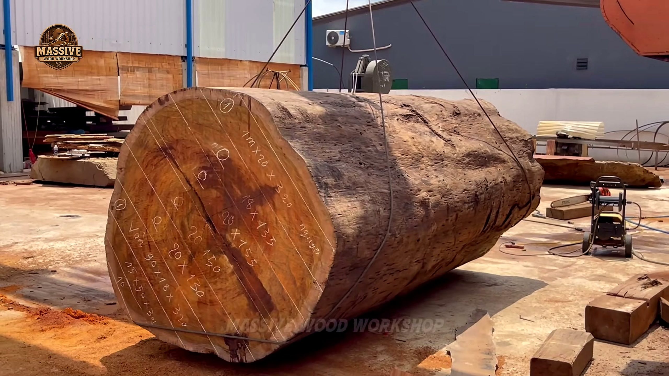 giant timbers with layout marks on the end grain and a pressure washer beside the log