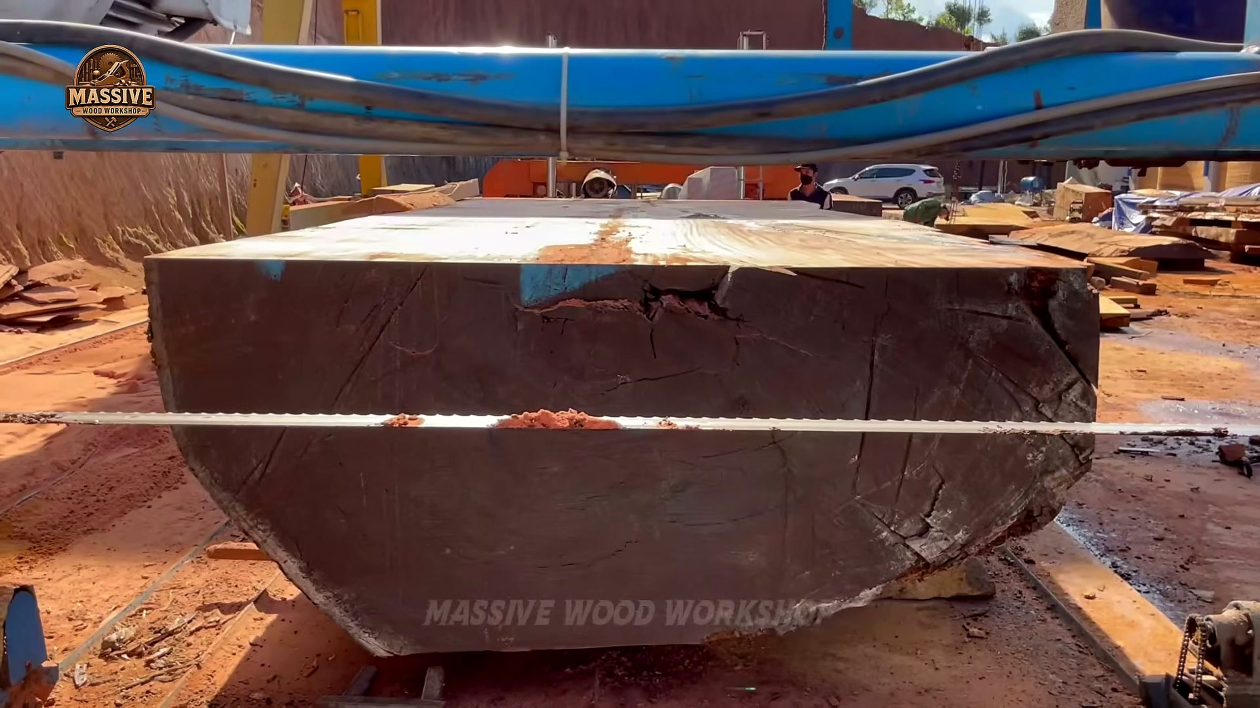 giant timbers squared into a block while the band saw blade cuts a slab