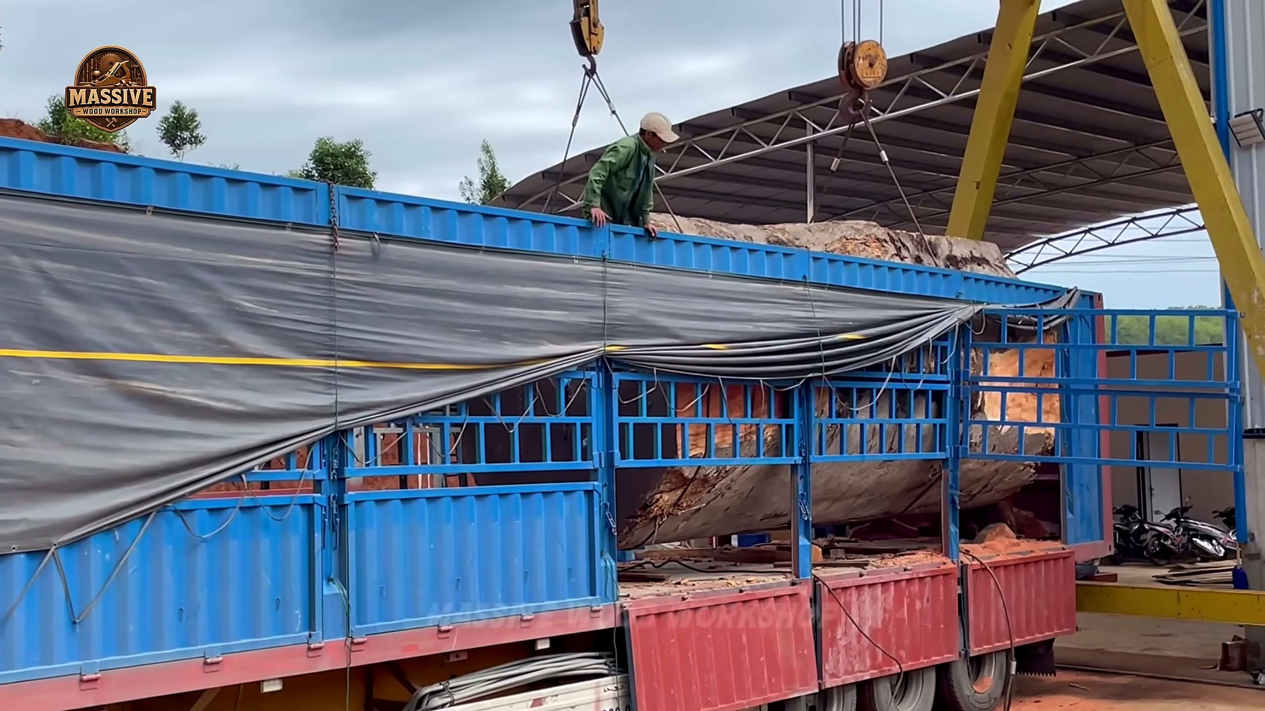 giant timbers being rigged on a flatbed truck under a gantry crane
