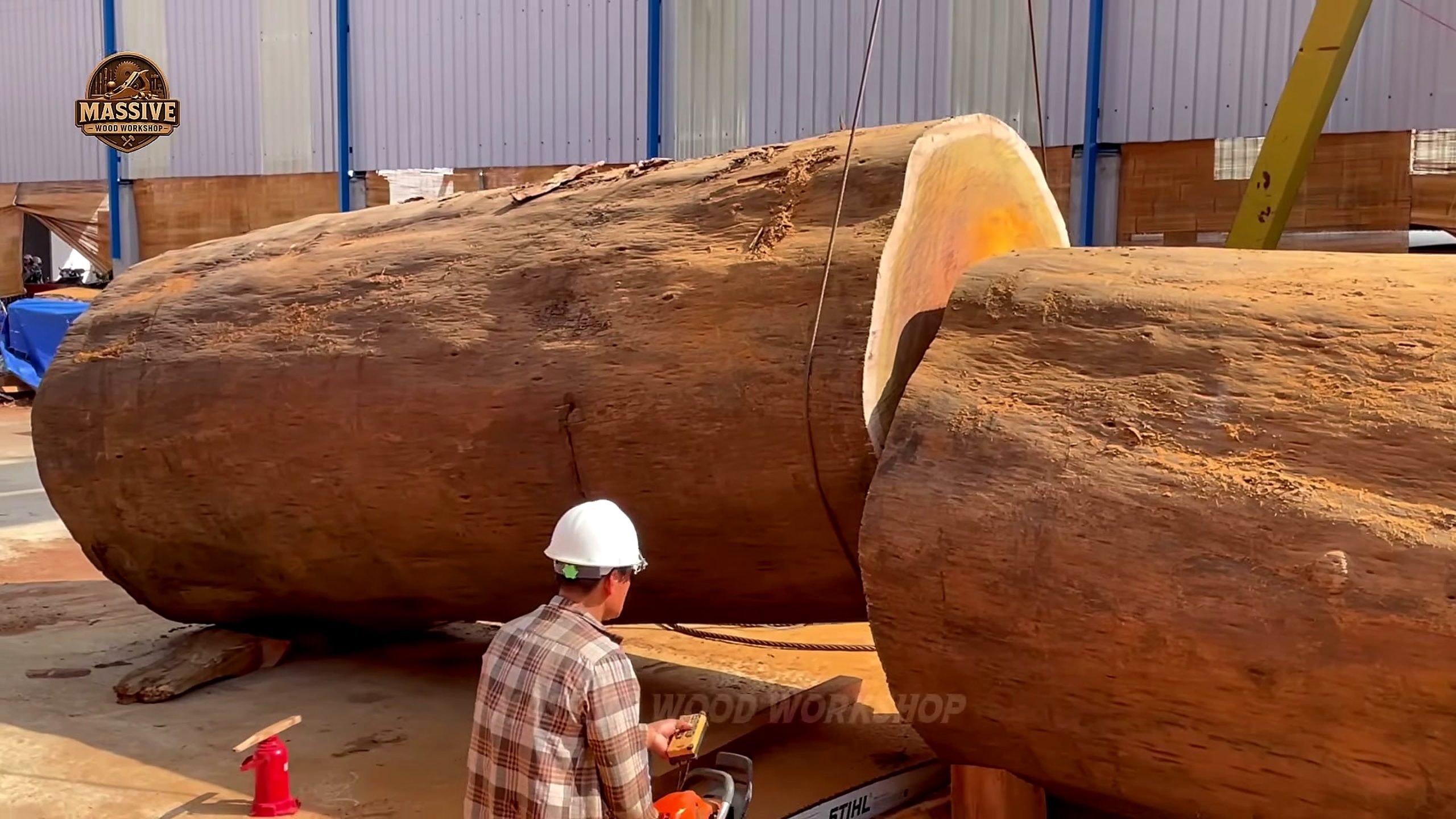 giant timbers resting in the mill yard while a worker in a hard hat inspects them